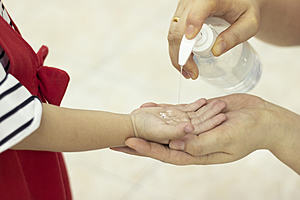 an adult applying hand sanitiser to a young child's hand