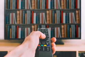 TV remote pointing at TV showing a bookcase full of books