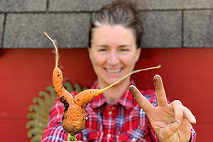 Una mujer sostiene una zanahoria deforme