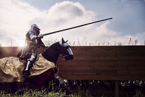 A historical interpreter dressed as a knight sat atop a horse participates in a reenactment of a Tudor joust. 