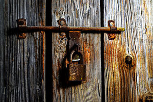 A rusted padlock on rotting timber