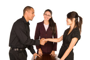 Diverse group of young professionals shaking each others' hands in agreement.