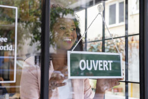 French shop worker turning open/ouvert sign over