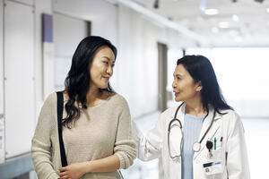 Smiling mature doctor talking to woman at a corridor in hospital.