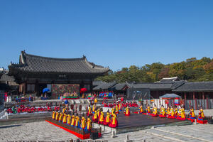 Korean royal court music: male and female performers in traditional dress stand in front of a pagoda and play music on traditional Korean instruments.