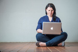 Woman sitting cross-legged on the floor working on a laptop 
