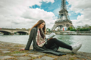 Girl reading poetry in front of the Eiffel Tower