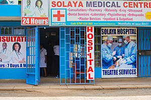 The entrance to a hospital called Solaya medical centre in Kenya. Building is blue with blue railings around and there is detail on the hospital signage about the services offered at the hospital which is a 24 hour 7 days a week hospital