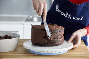 Putting icing on a chocolate cake