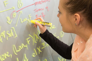 Photo of a STEM student writing in mathematical vocabulary and equations on a white board